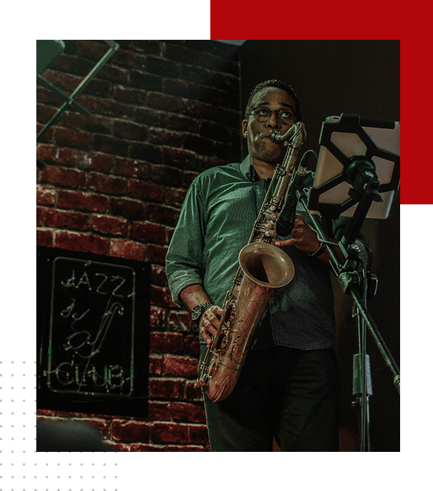 A man holding a saxophone in front of a microphone.