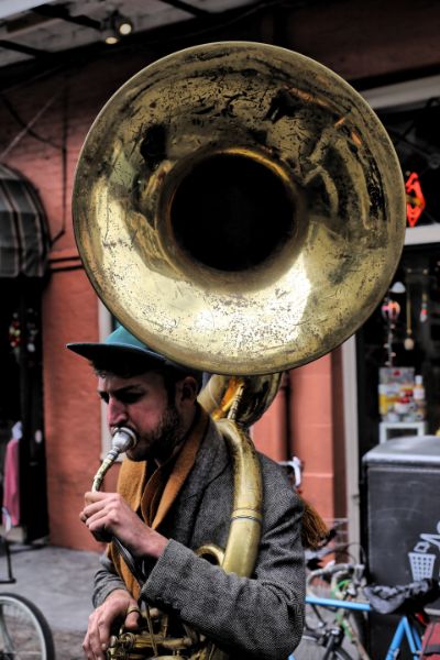 A man with a hat and jacket on holding a trombone.